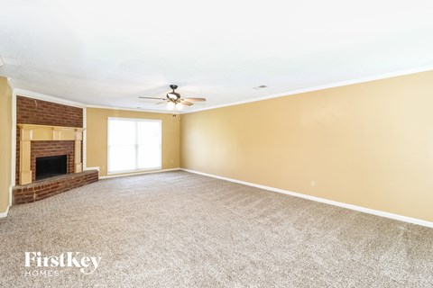 a empty living room with a brick fireplace and a ceiling fan