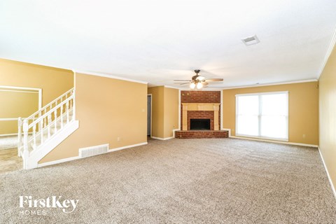 a carpeted living room with a fireplace and a ceiling fan
