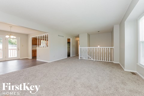 A spacious living room with a carpeted floor and white walls.