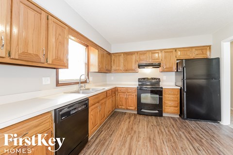 A kitchen with wooden cabinets and a black refrigerator.