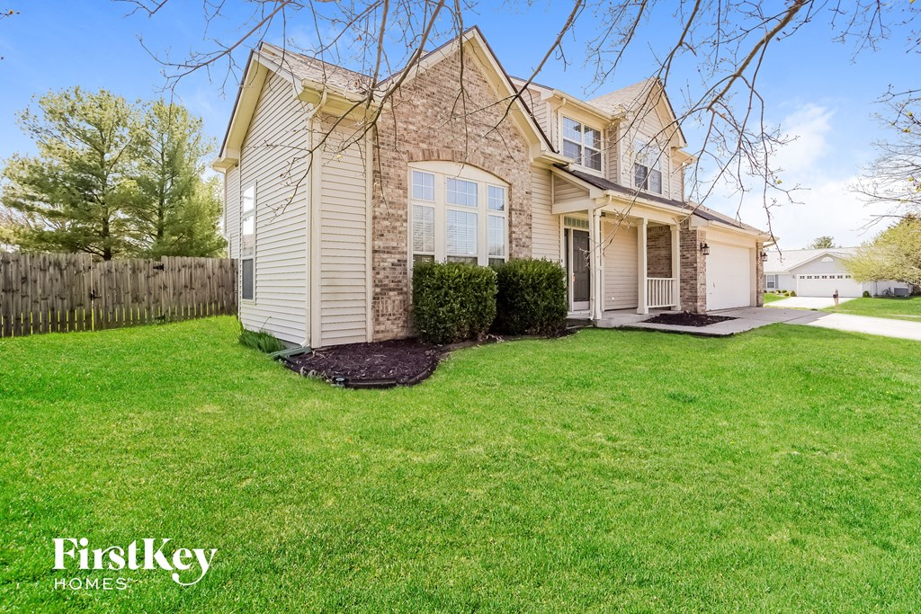 A house with a well-kept lawn and a fence in the background.
