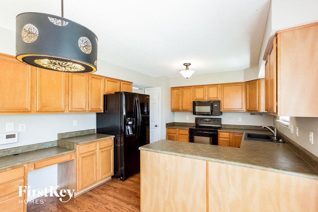 A kitchen with wooden cabinets and a black fridge.