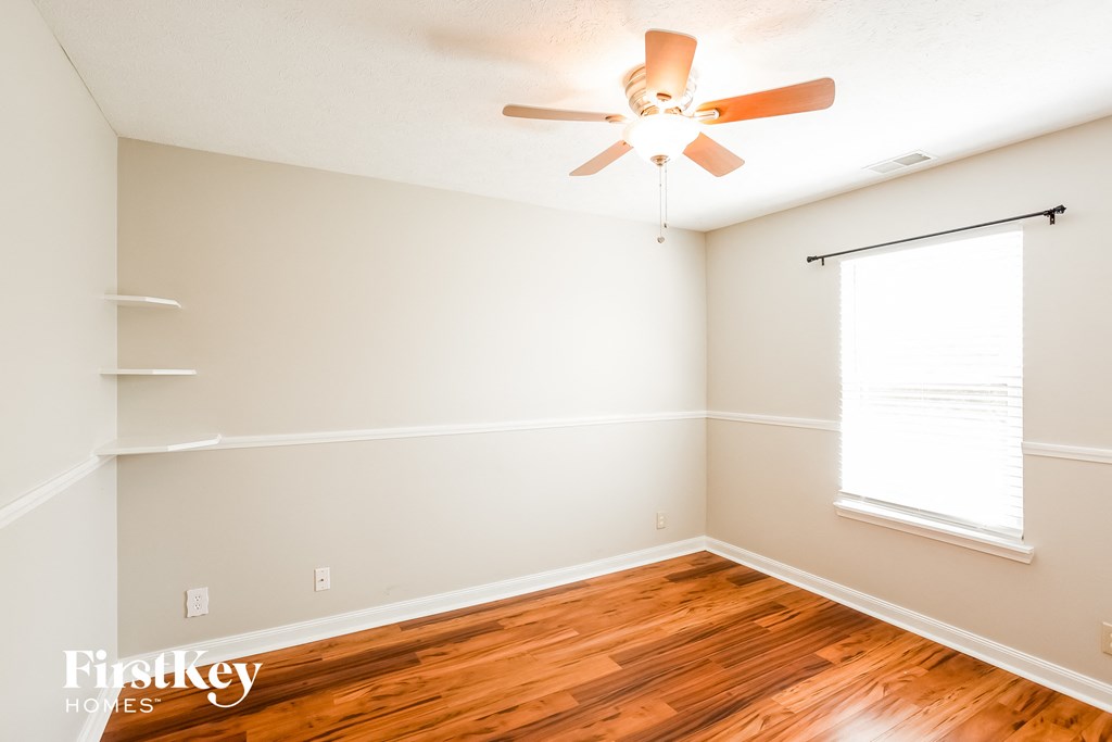 A room with a ceiling fan and wooden floors.