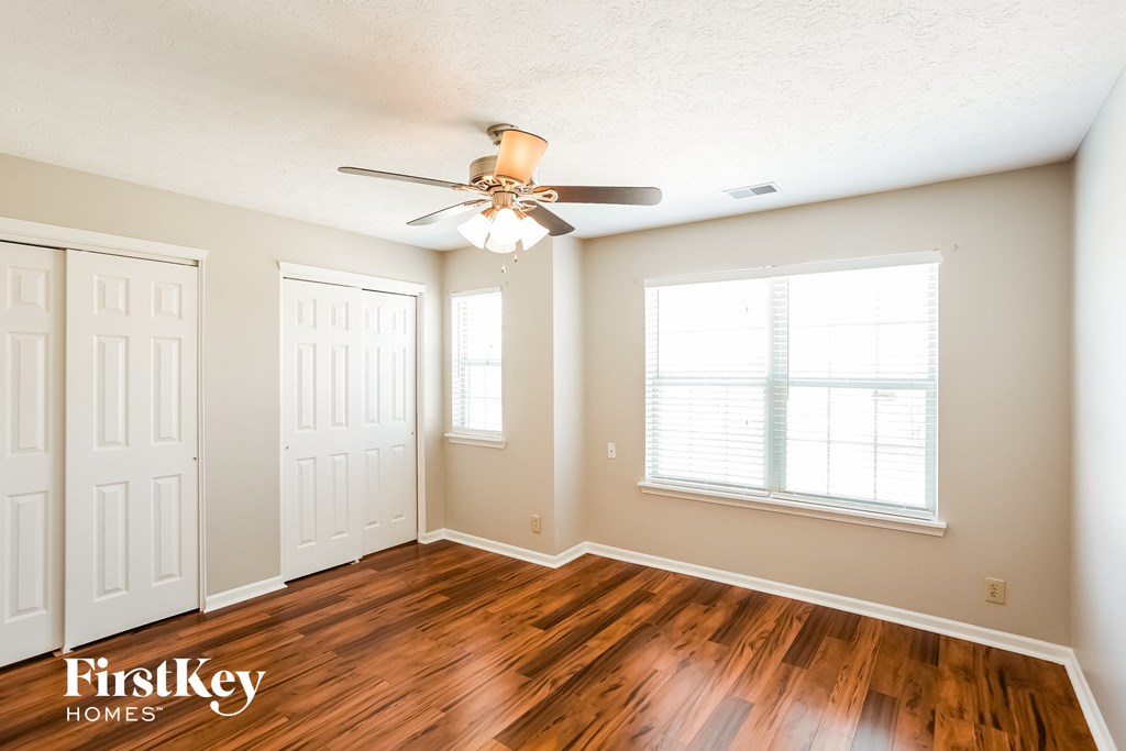 A room with a ceiling fan and wooden floors.