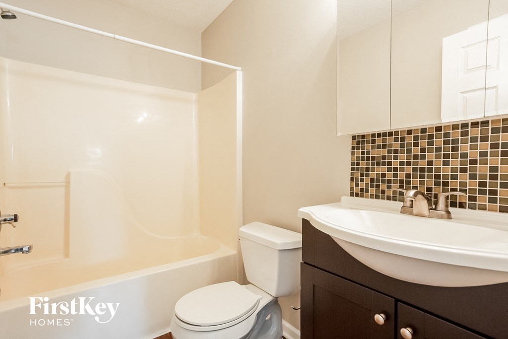 A white toilet sits next to a bathtub in a bathroom.