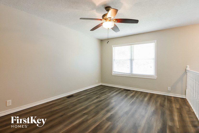 the living room of an empty house with a ceiling fan and a window