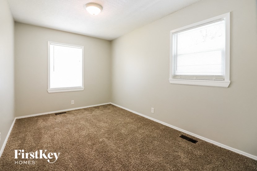 a empty room with carpet and two windows
