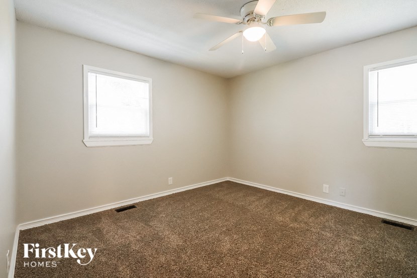 an empty room with a ceiling fan and two windows