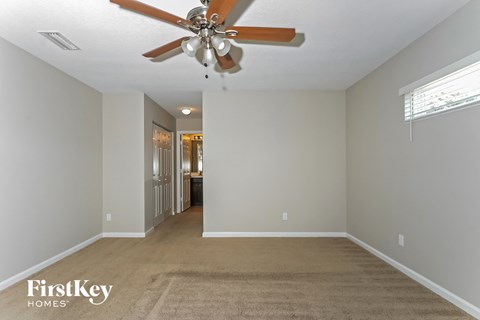 a living room with a ceiling fan and a carpet