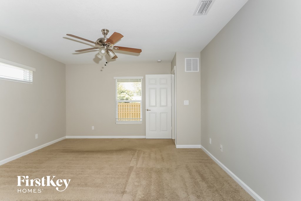 a empty living room with a ceiling fan and a white door