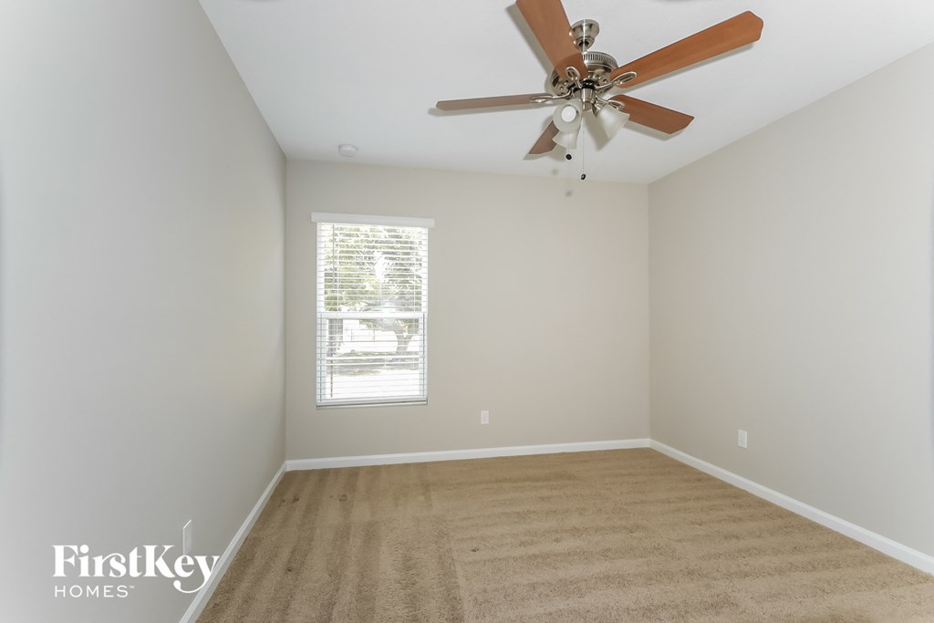 an empty room with a ceiling fan and a window