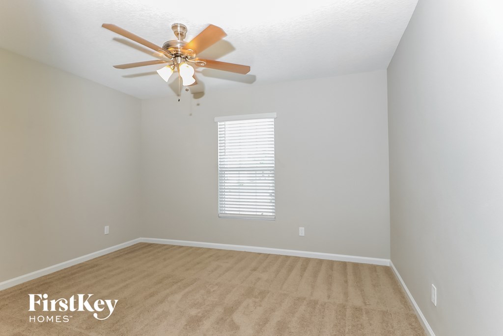 a bedroom with a ceiling fan and a carpeted floor