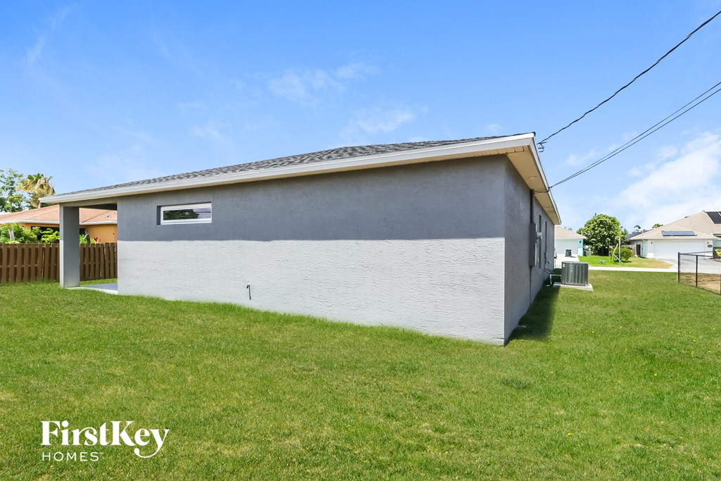the outside of a house with a green lawn and a white wall