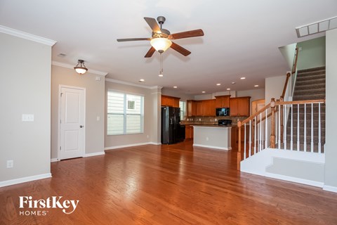 A spacious living room with wood floors and a ceiling fan.