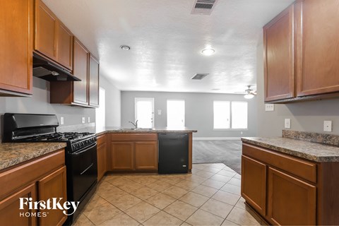 a kitchen with wood cabinets and black appliances and tiled floor