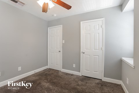 a bedroom with two doors and a carpeted floor and a ceiling fan