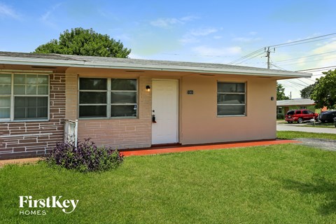 a small brick house with a white door and a lawn