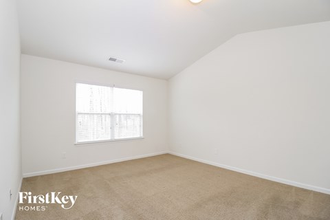 a bedroom with white walls and carpet and a window