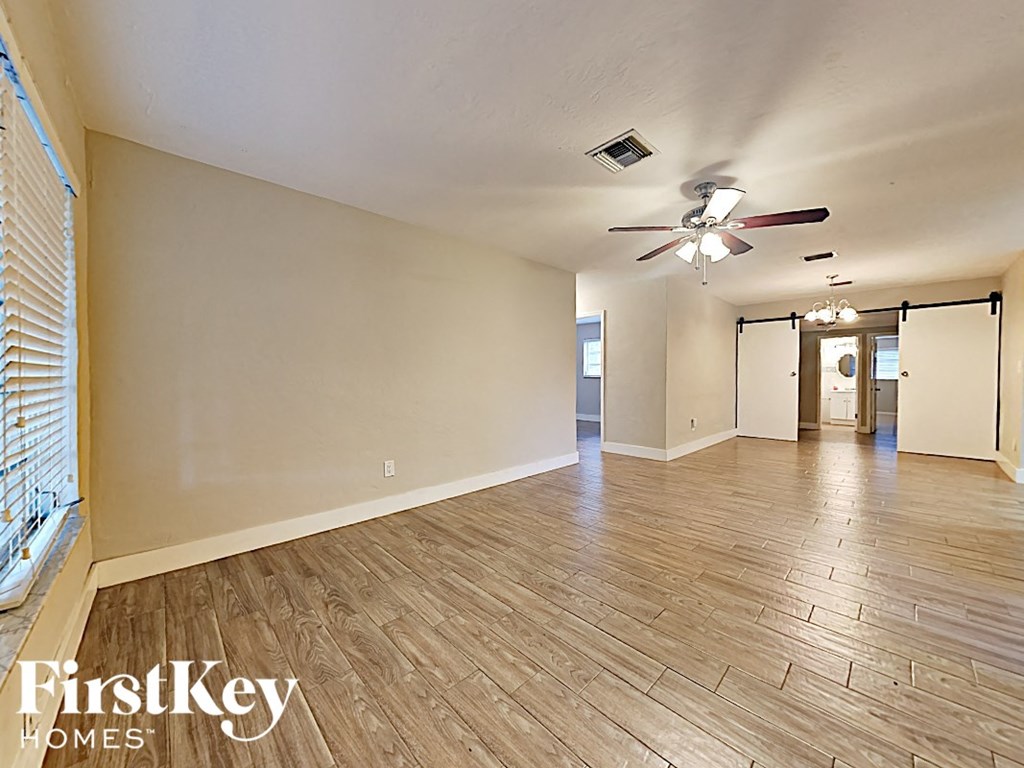 a spacious living room with wood floors and a ceiling fan