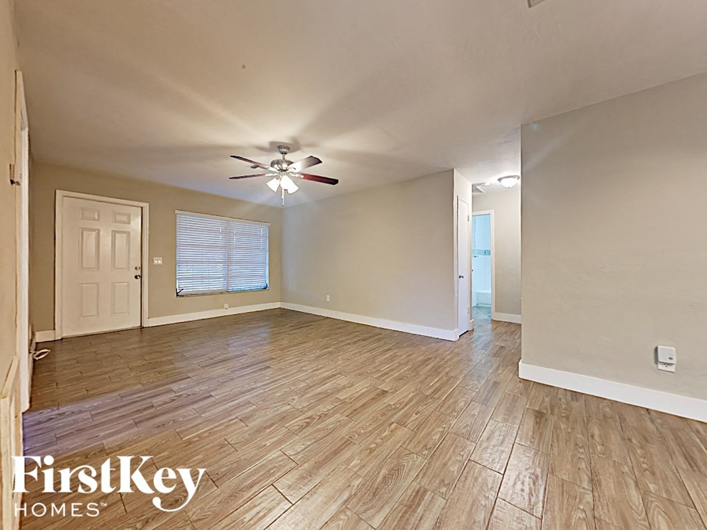 the living room and dining room with wood flooring and a ceiling fan