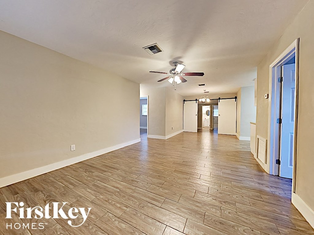 a spacious living room with wood floors and a ceiling fan