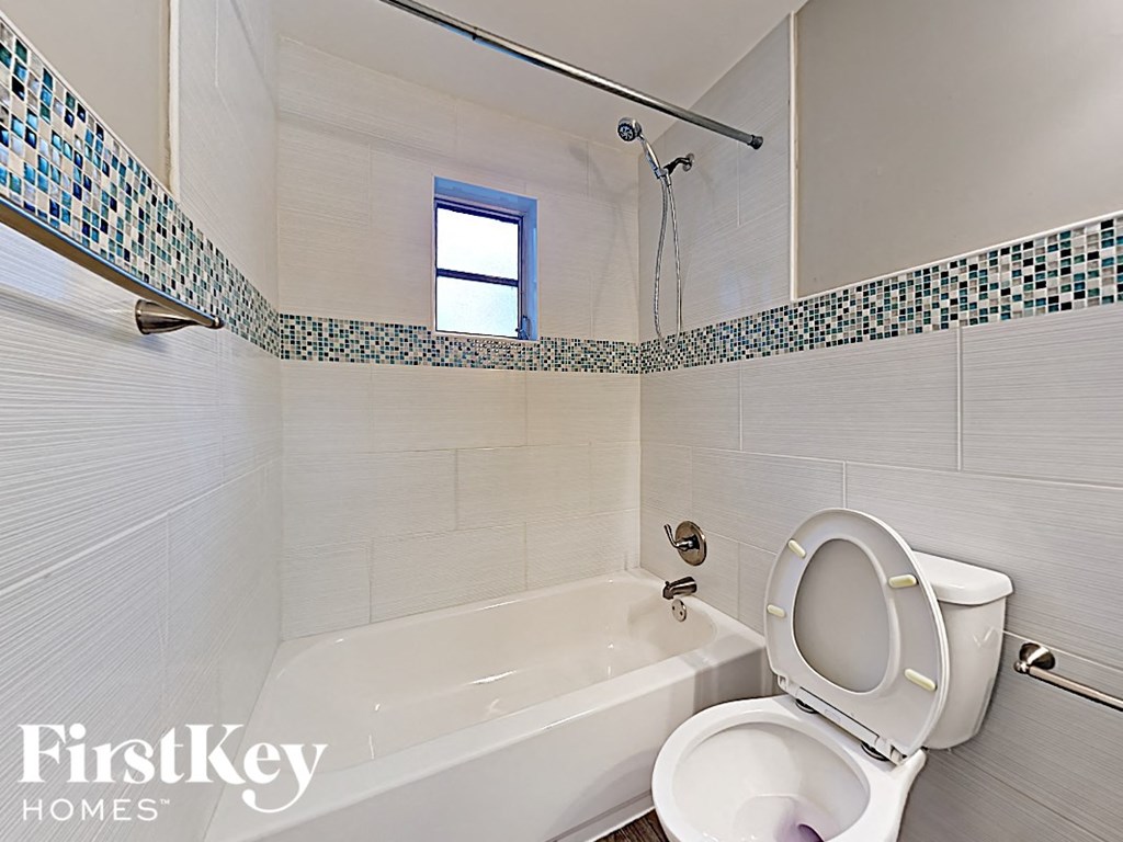 a white bathroom with a toilet and a bath tub