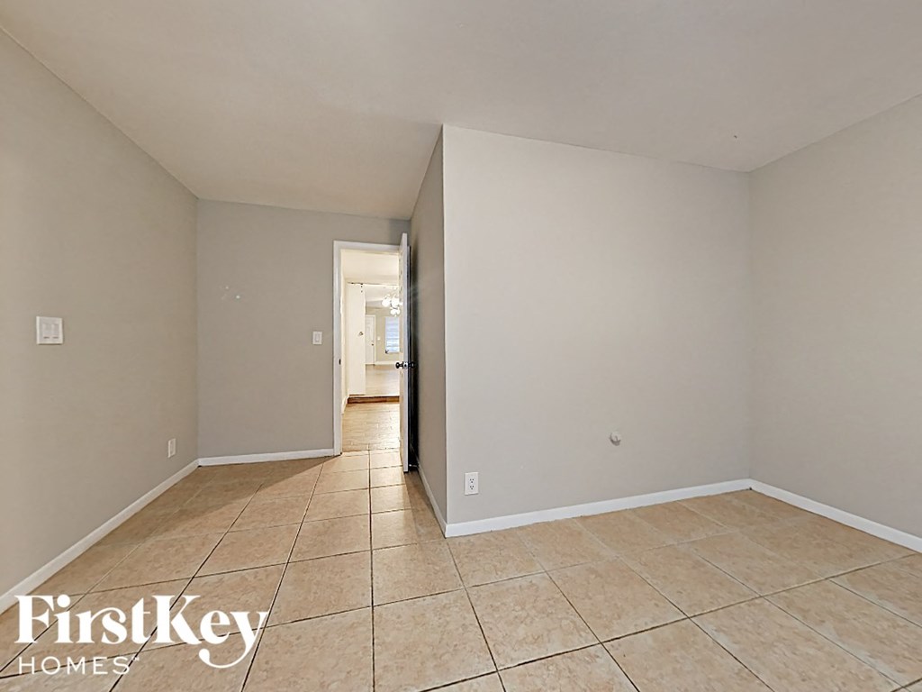 the spacious living room has tile flooring and white walls