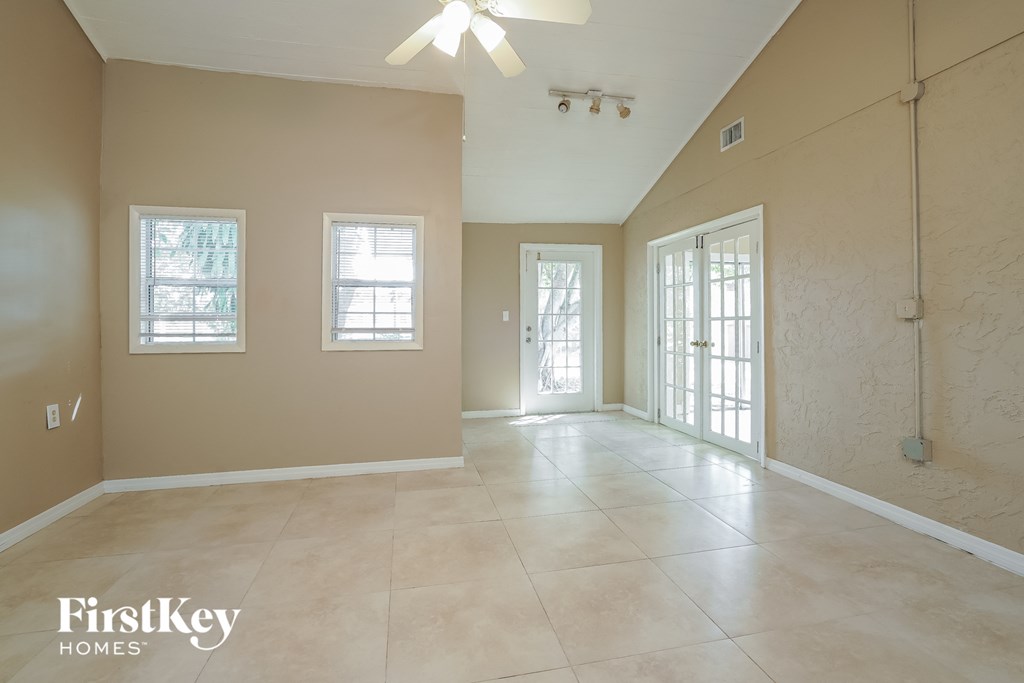 A spacious room with a ceiling fan and three windows.