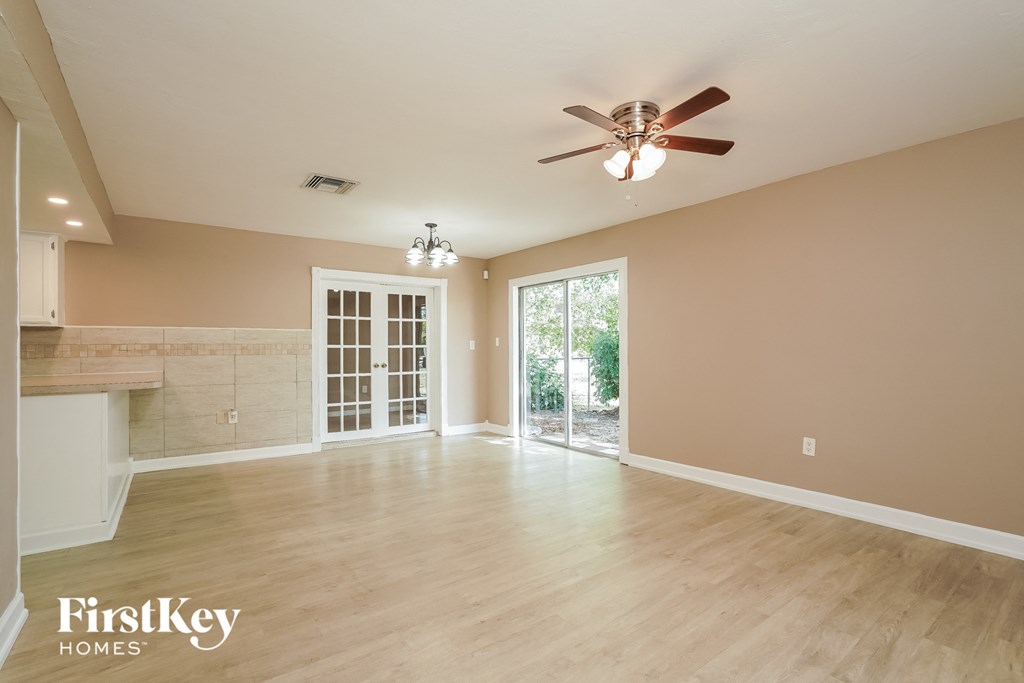 A spacious room with a ceiling fan and sliding glass doors.