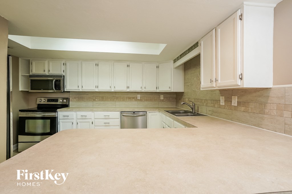 A kitchen with white cabinets and a beige countertop.