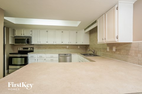 A kitchen with white cabinets and a beige countertop.