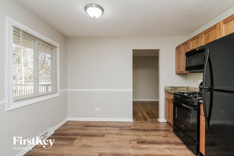 an empty kitchen with black appliances and wood flooring