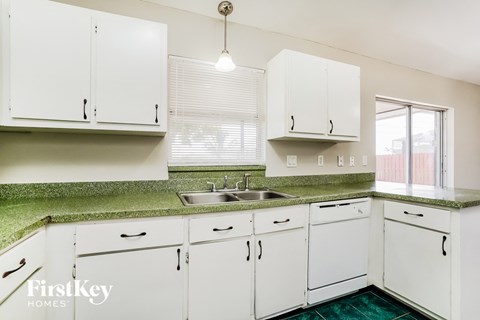 A kitchen with white cabinets and a green counter top.