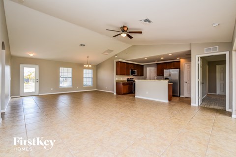 A spacious living room with a kitchen in the background.