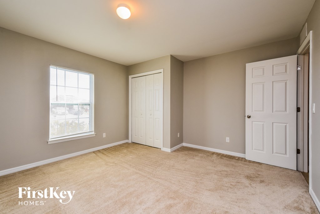 A room with a white door and a window with a view of a building outside.