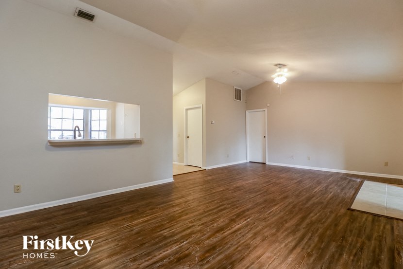an empty living room with wood flooring and a window