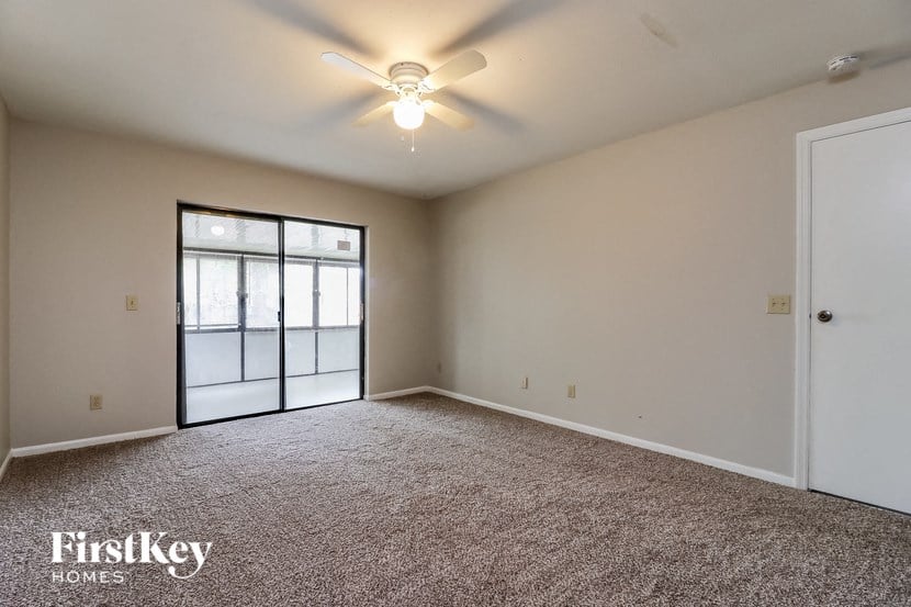 an empty living room with a ceiling fan and a glass door