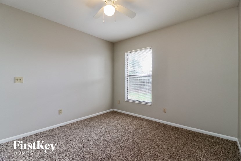 an empty room with a window and a ceiling fan