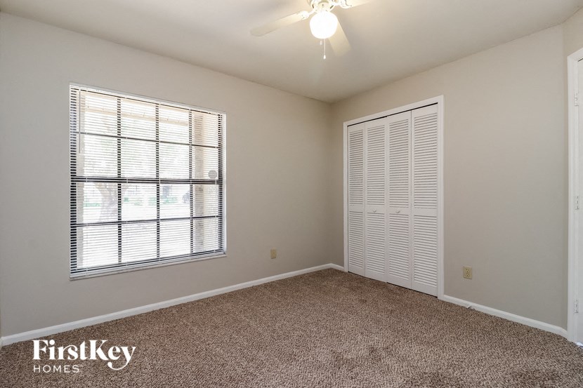 a bedroom with a large window and a ceiling fan