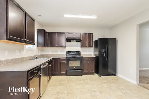 A kitchen with dark brown cabinets and a black refrigerator.