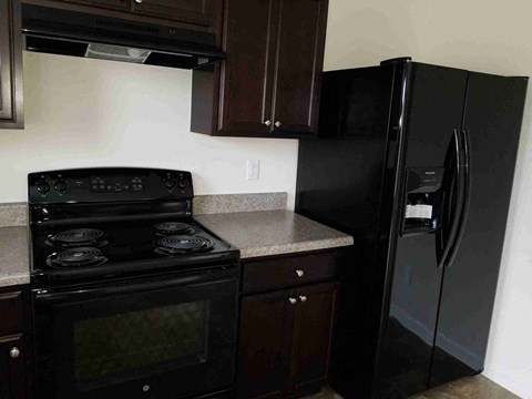 A black stove and oven in a kitchen with a black refrigerator.