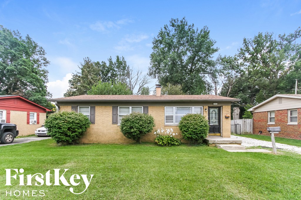 a brick house with a lawn and some bushes