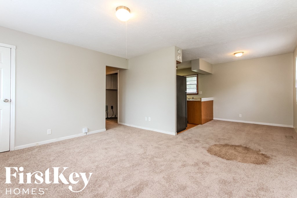 an empty living room with carpet and a door to a closet