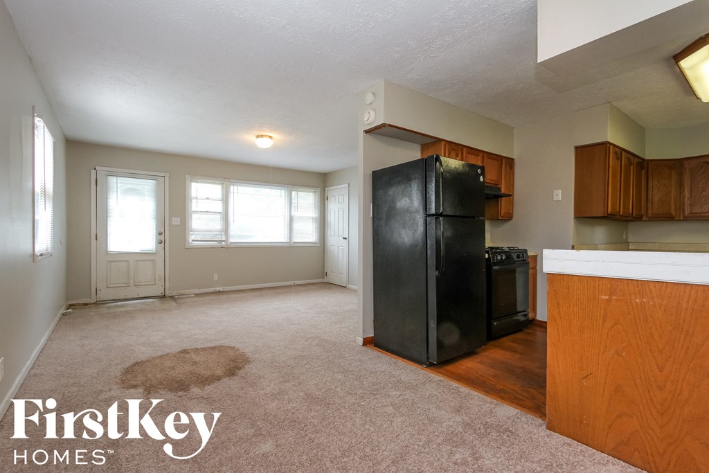 an empty kitchen with a black refrigerator in the corner