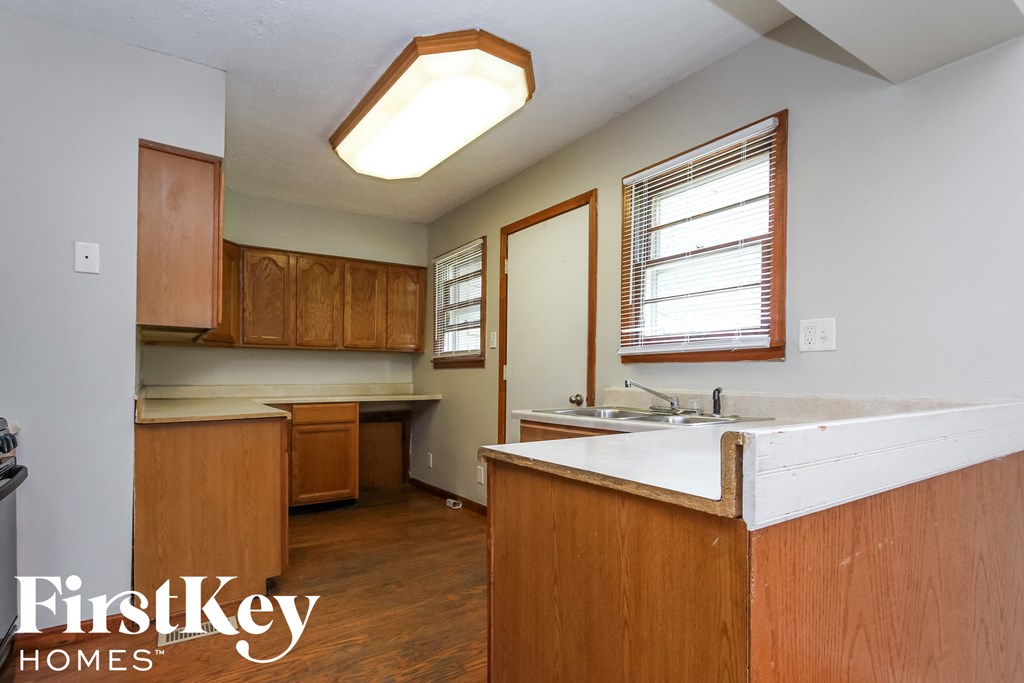 an empty kitchen with white counter tops and wooden cabinets
