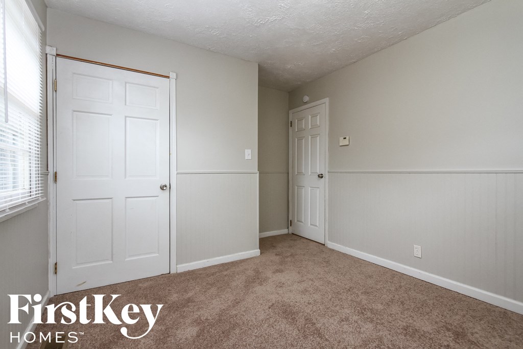 a bedroom with white doors and carpet and a door to a closet