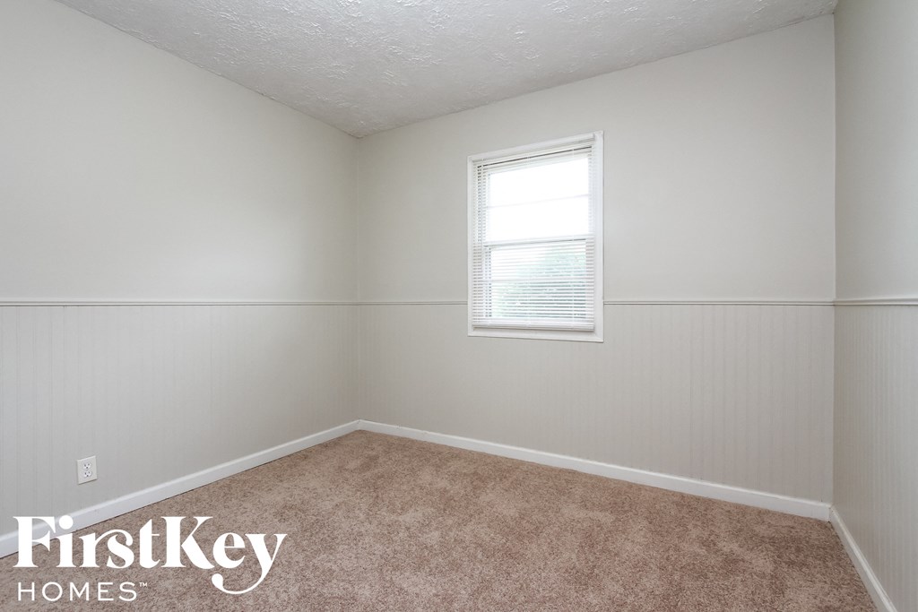 a bedroom with a window and a carpeted floor