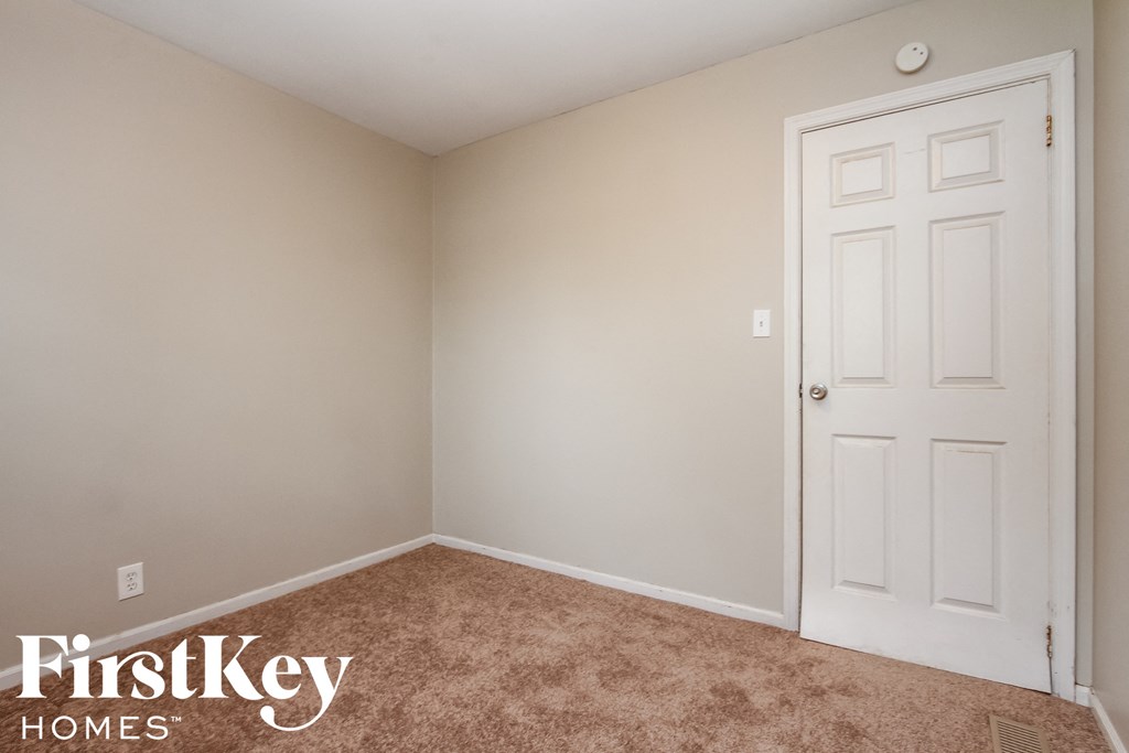a bedroom with a white door and a carpeted floor