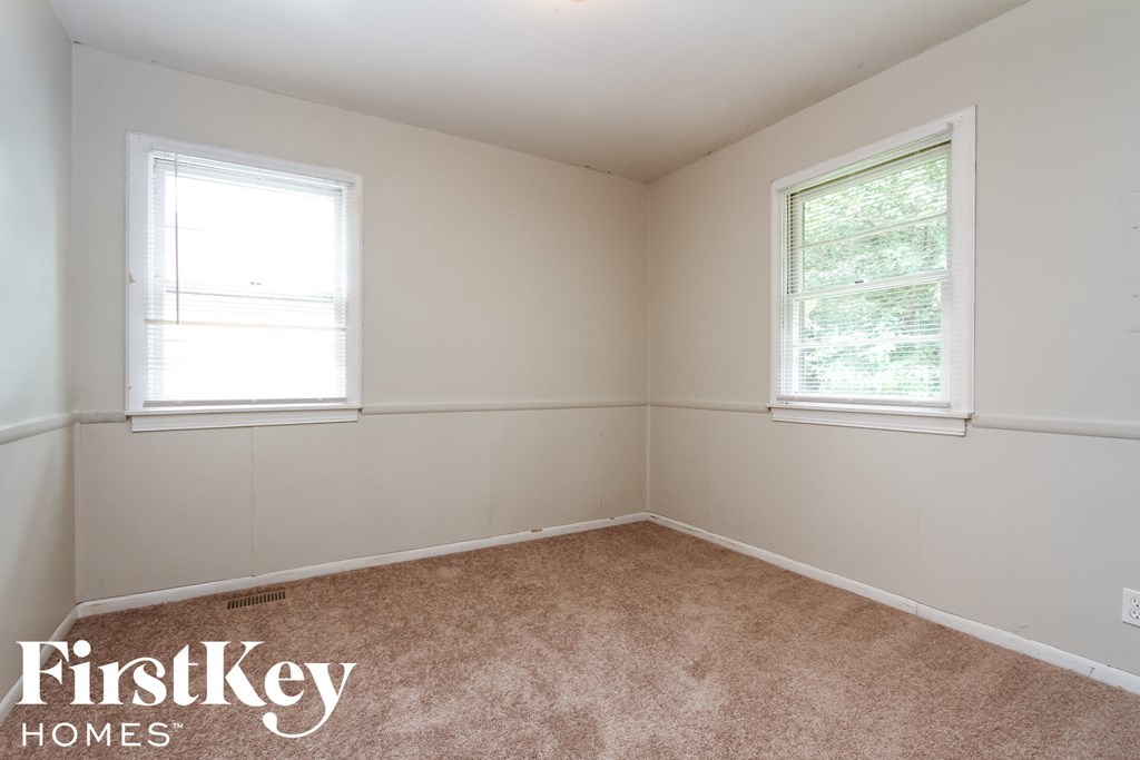 a bedroom with two windows and a carpeted floor