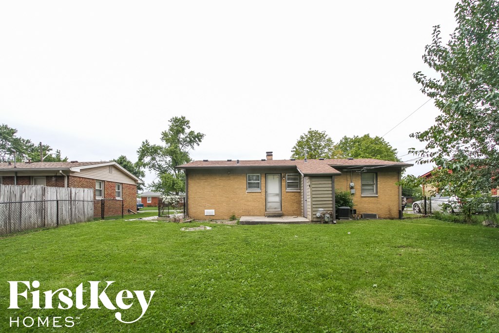 a small brick house in a backyard with a grassy yard